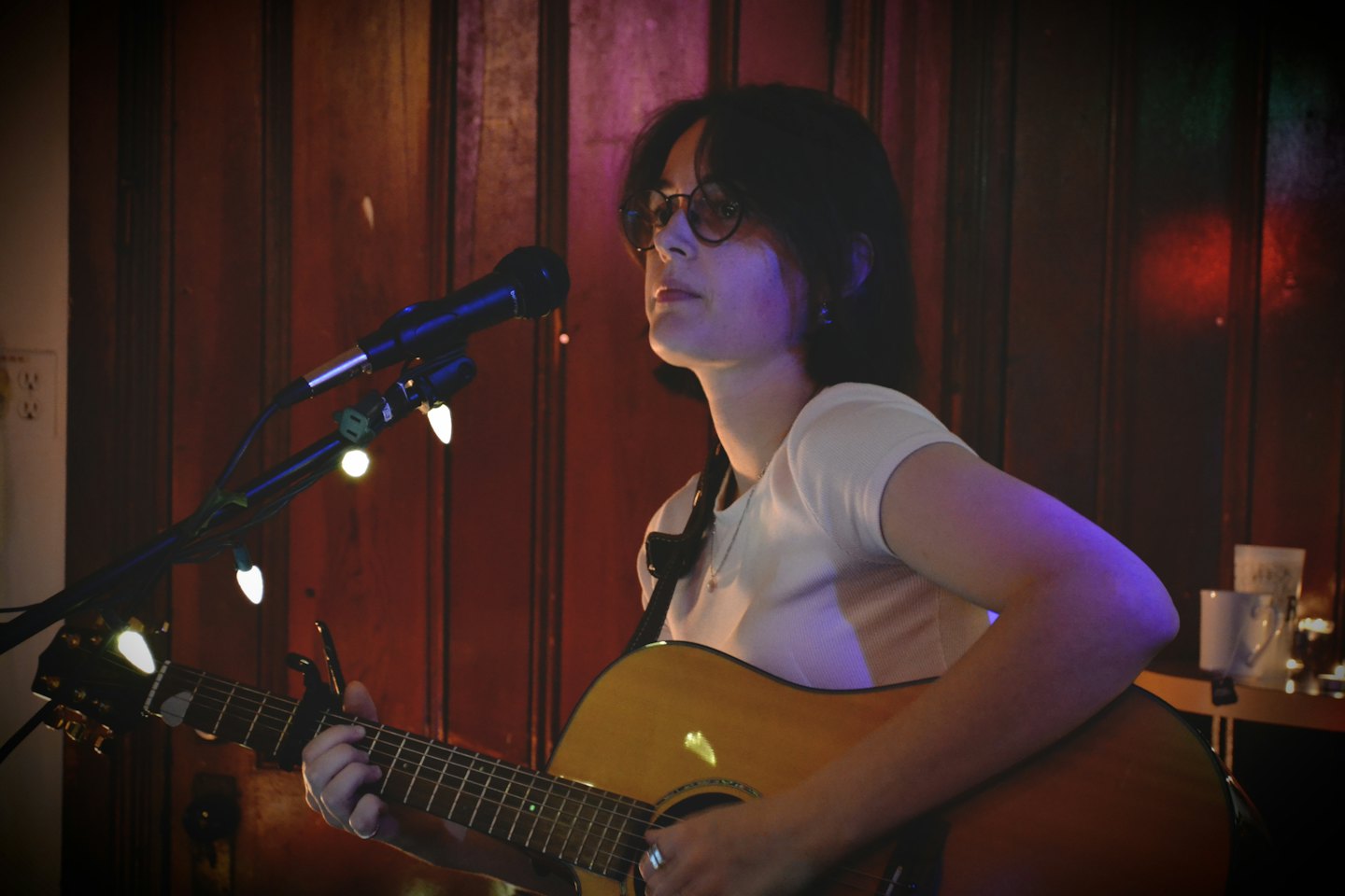 Woman singing and playing guitar on stage.