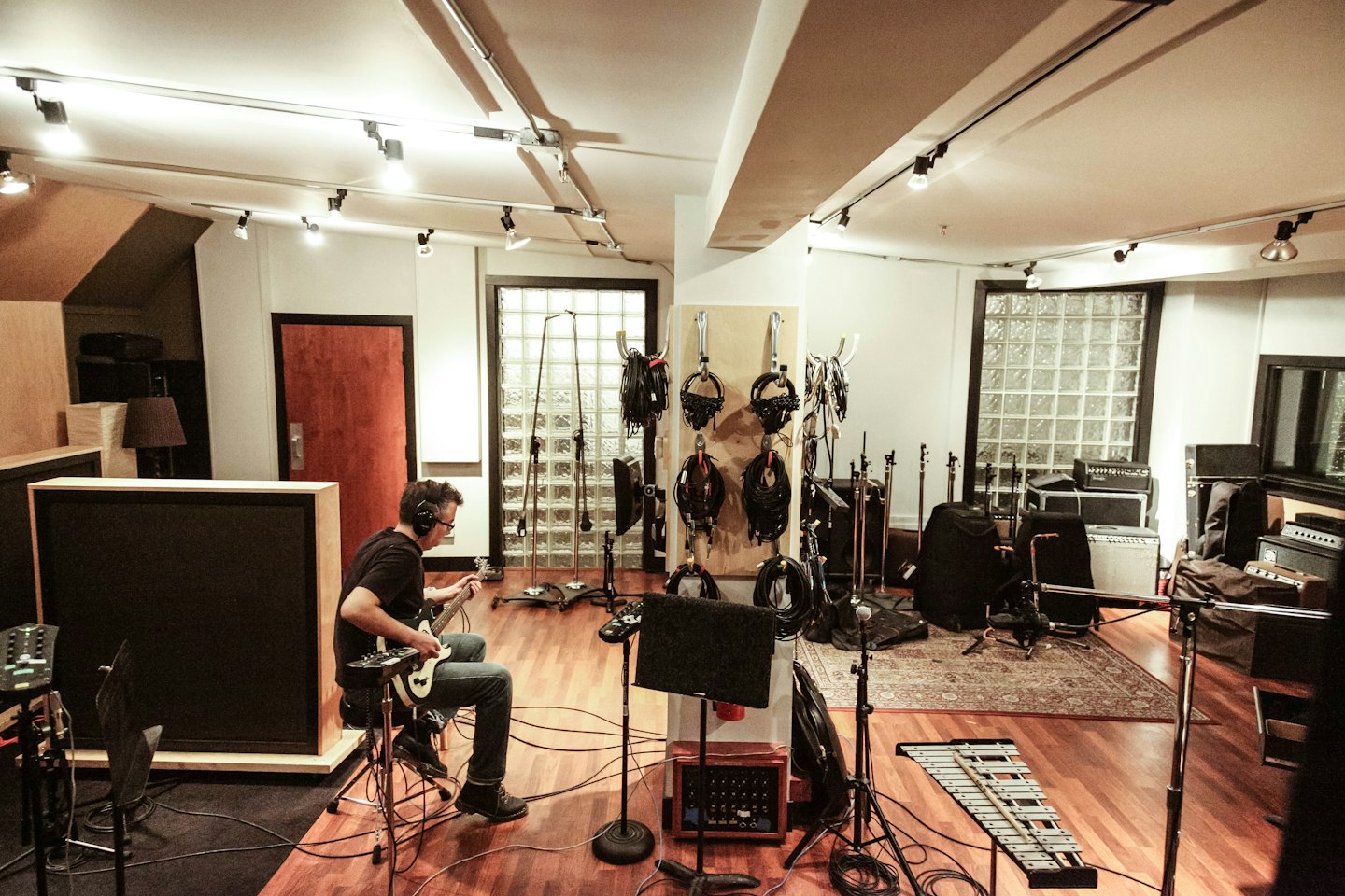 Man wearing headphones plays electric guitar in a recording studio.