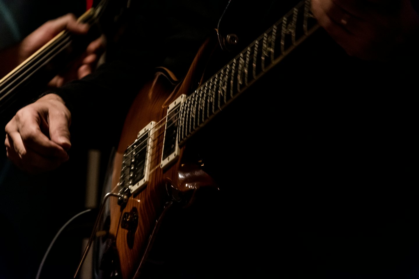 Two people play acoustic guitars during a musical rehearsal.