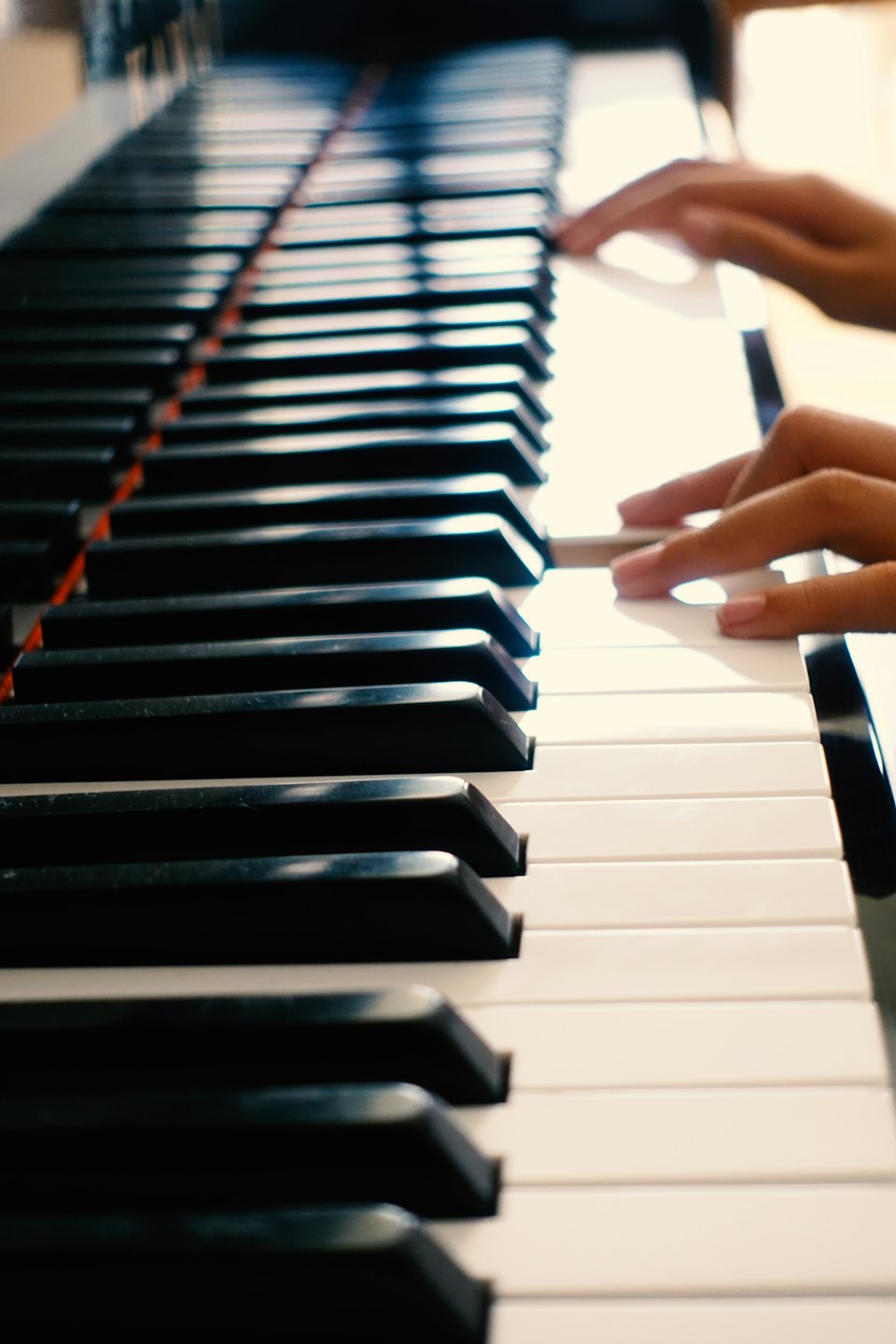 Hands playing a piano with black and white keys.