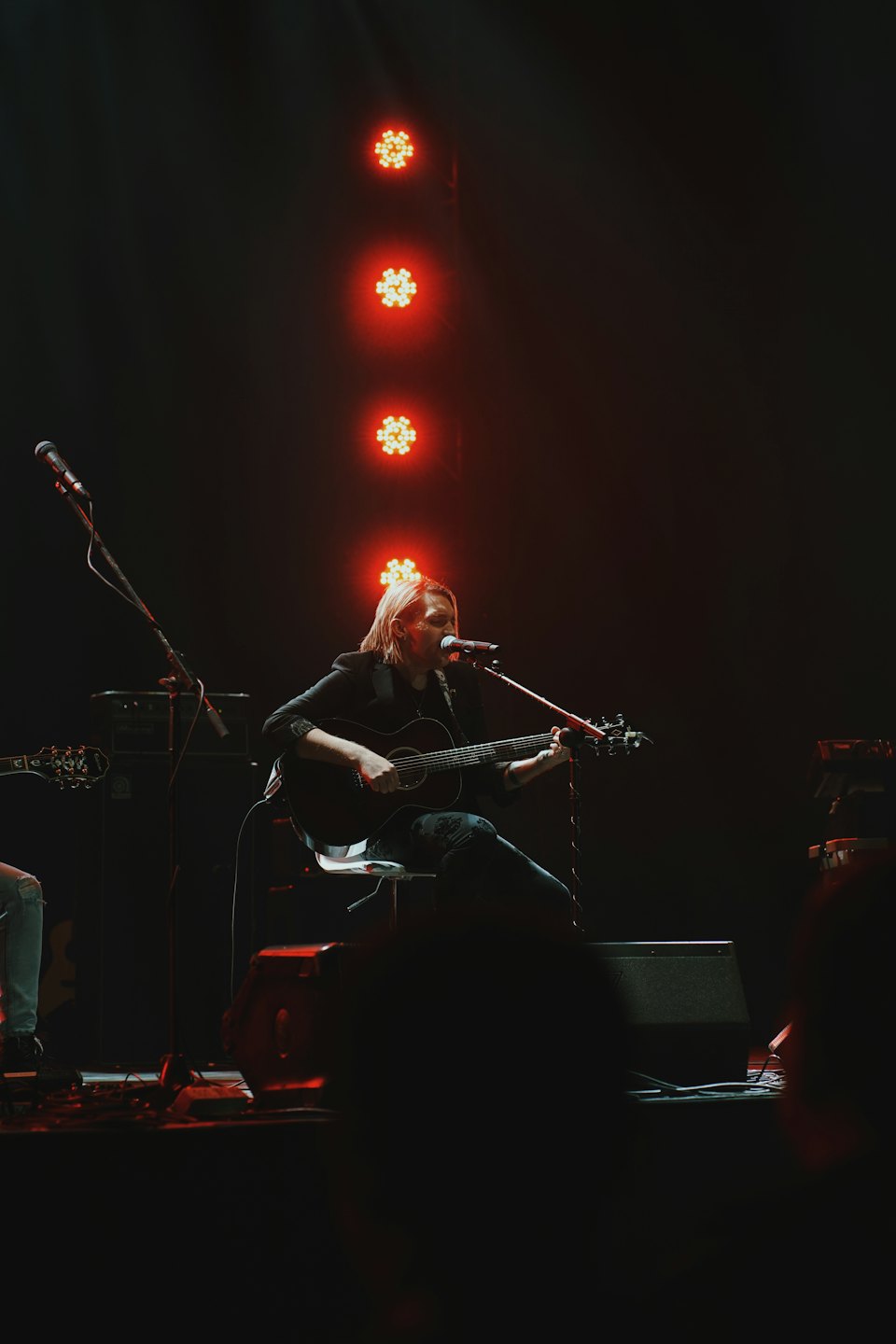 Musician plays acoustic guitar and sings into a microphone.